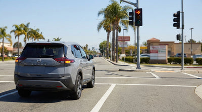 A car rental stopped at a red right-turn arrow at a sunny California intersection