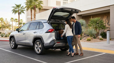 Traveler loading a suitcase into a car hire vehicle outside a brightly lit Las Vegas Strip hotel entrance