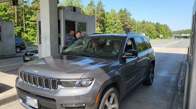 A white car rental drives under an electronic toll sign on a Pennsylvania highway