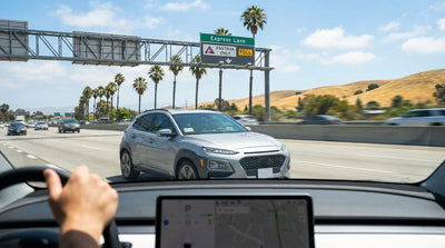 A car rental drives on a sunny California freeway with signs for the express toll lanes ahead
