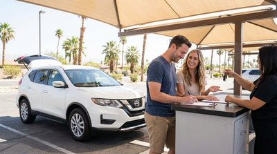 A smiling couple stands beside their convertible car hire on a sunny day in Las Vegas