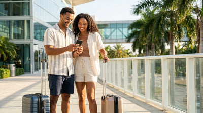 A smiling woman accepts the keys for her car hire from an agent at a rental counter in Miami