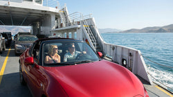 White car rental parked on the open deck of a passenger ferry crossing the water in California