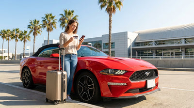 A person driving a convertible car rental along a sunny coastal highway in California