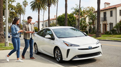 A modern car rental parked under tall palm trees on a bright, sunny street in Los Angeles