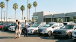 A red convertible car rental driving down a palm tree-lined street in Los Angeles