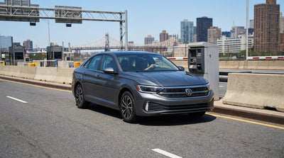 A car rental drives across the Brooklyn Bridge with the iconic New York City skyline in the background