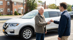 A smiling senior man holds up the keys to his car rental on a bustling street in New York