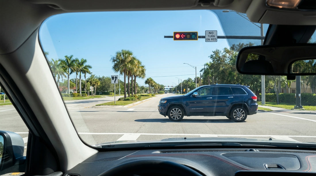 A car rental waiting at a red arrow light on a palm-lined street in sunny Florida