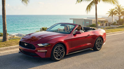 A red Mustang convertible car rental driving down a sunny, palm-lined street in Miami