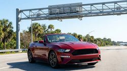 SunPass transponder on the dashboard of a car rental driving on a sunny Florida highway