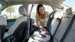 Young child sitting securely in a booster seat inside a California car rental parked near the beach