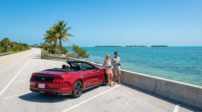 A white convertible car hire drives along the sunny Overseas Highway in Florida above stunning turquoise water