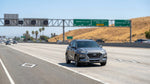 A car rental driving on a sunny California freeway with overhead signs for the HOV express lane
