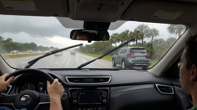 Driver's view from a car rental in a Florida downpour, with rain obscuring the road and wipers still