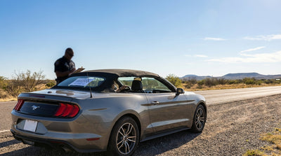 Police car with flashing lights pulled over a car hire vehicle on a sunny Texas highway shoulder