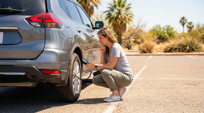 A person checks the tyre pressure with a gauge on their Texas car hire at a gas station pump
