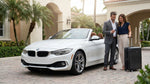 A sleek convertible car rental parked beside tropical palm trees on a sunny street in Miami