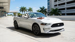 A stylish car hire convertible parked along a sun-drenched Ocean Drive in Miami with palm trees