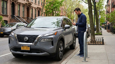 A person looking at a parking meter next to their car hire on a busy street in New York City