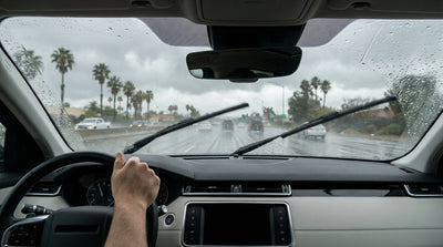 Driver's point of view from a car rental as wipers smear heavy rain across a windshield on a California highway