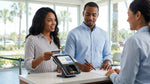 Person entering a PIN into a credit card reader at an Orlando car hire counter