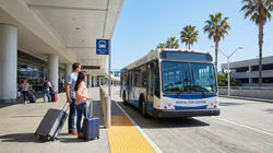 Passengers boarding a car rental shuttle bus outside LAX Terminal 7 arrivals in Los Angeles