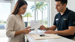 A person at a Florida car rental counter reviews paperwork before receiving the keys