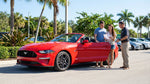 A convertible car hire driving down a scenic, palm-lined coastal road in sunny Florida