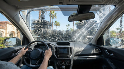 A modern car hire entering a drive-through car wash under the bright sun in Los Angeles