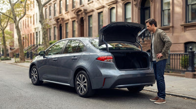 A white car rental parked on a busy New York City street with yellow cabs and skyscrapers in the background