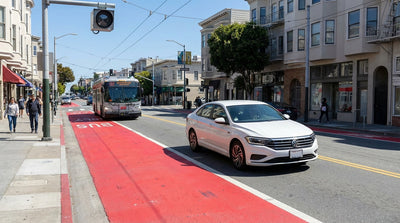 A car rental driving in downtown San Francisco traffic next to a bright red bus-only lane