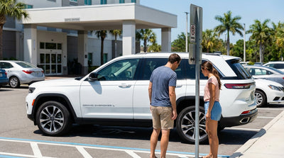A red and white tow-away zone sign in a sunny Florida hotel parking lot with a silver car hire parked nearby