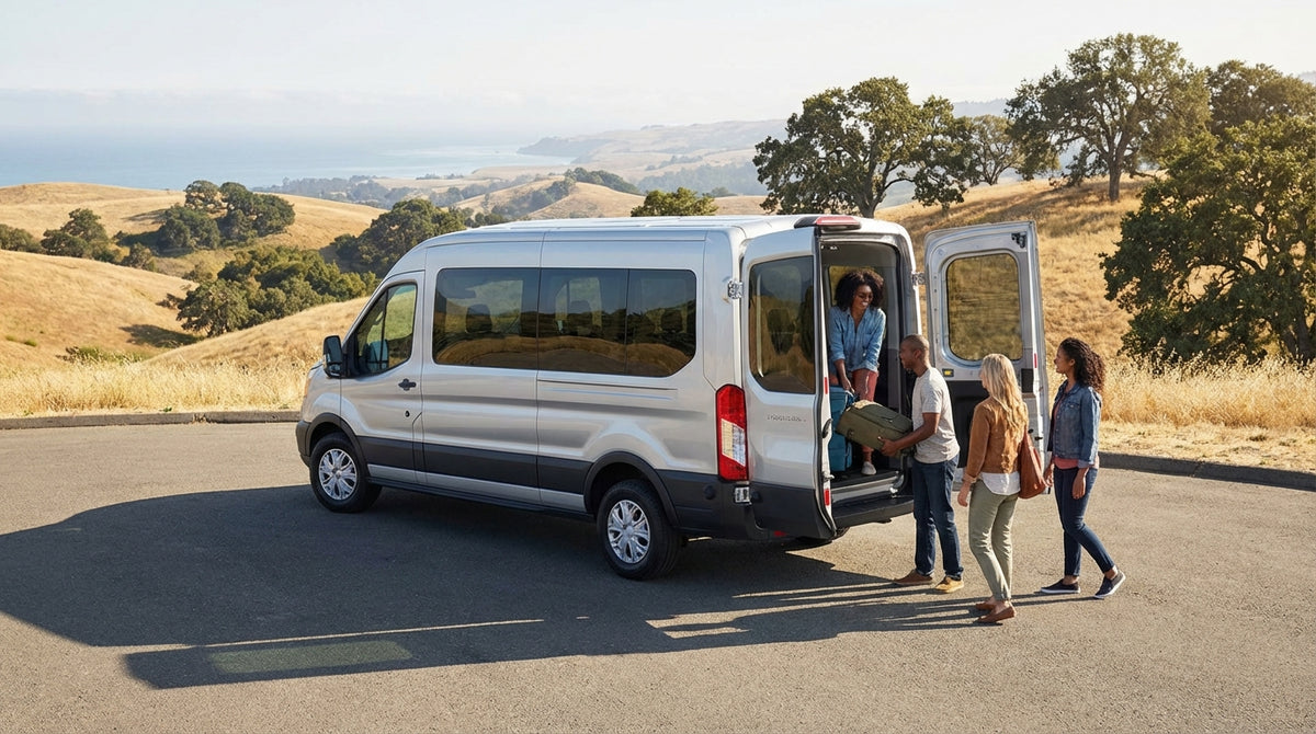 A large passenger van car rental parked on a scenic overlook of the California coast at sunset