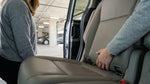 A person leans into the back of a car rental to inspect the seats on a New York City street