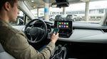 A driver's hands plugging an iPhone into the dashboard of a car rental vehicle at an airport in New York