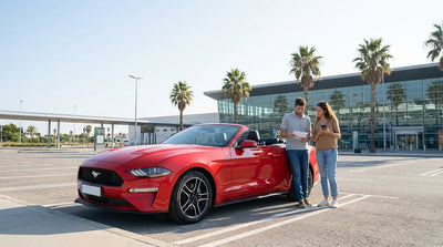 A red convertible car hire driving on a sunny day along a scenic coastal highway in California