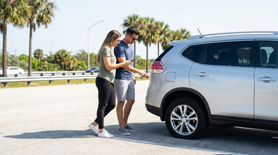 A white convertible car rental driving down a sunny, palm-lined road in Miami