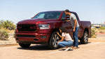 A person inspects the tyre of their car hire vehicle on a dusty road in the Texas countryside at sunset