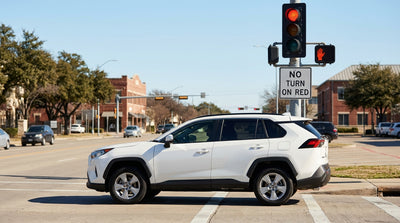 A car hire stopped at a red light on a city street in Texas with a pedestrian crossing signal