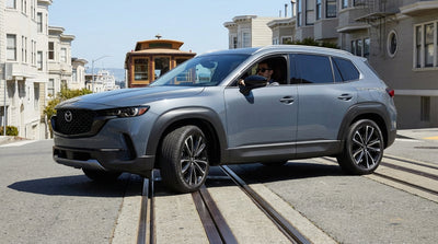 A car hire drives over the steel cable-car tracks on a steep street in San Francisco