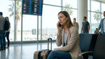 Traveler with a suitcase checking their phone at an Orlando airport car hire desk