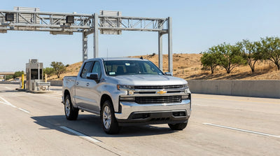 A car rental drives on a sunny Texas highway with an electronic toll road sign overhead