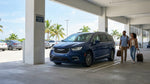 Traveler pulling a suitcase toward a parked vehicle in a Miami airport car rental lot