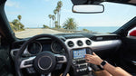 A person adjusts the rearview mirror of their car rental on a sunny, palm-tree-lined street in California