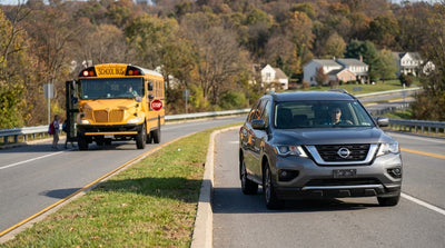 A car hire stopped for a yellow school bus with flashing lights on a divided highway in Pennsylvania