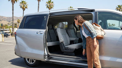 A woman inspects the back seats of her car rental SUV under palm trees in Los Angeles