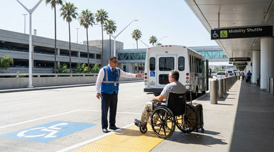 Airport employee assists a traveler in a wheelchair towards the car rental shuttle stop at LAX in Los Angeles