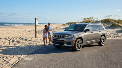 A 4x4 car rental parked on a wide sandy beach in Texas with tire tracks leading towards the ocean