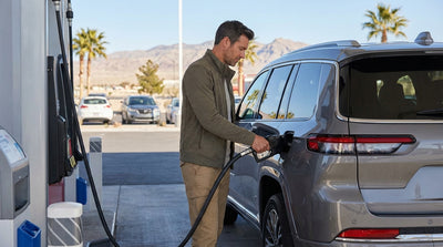A red convertible car hire driving down the Las Vegas Strip at dusk with bright casino lights in the background